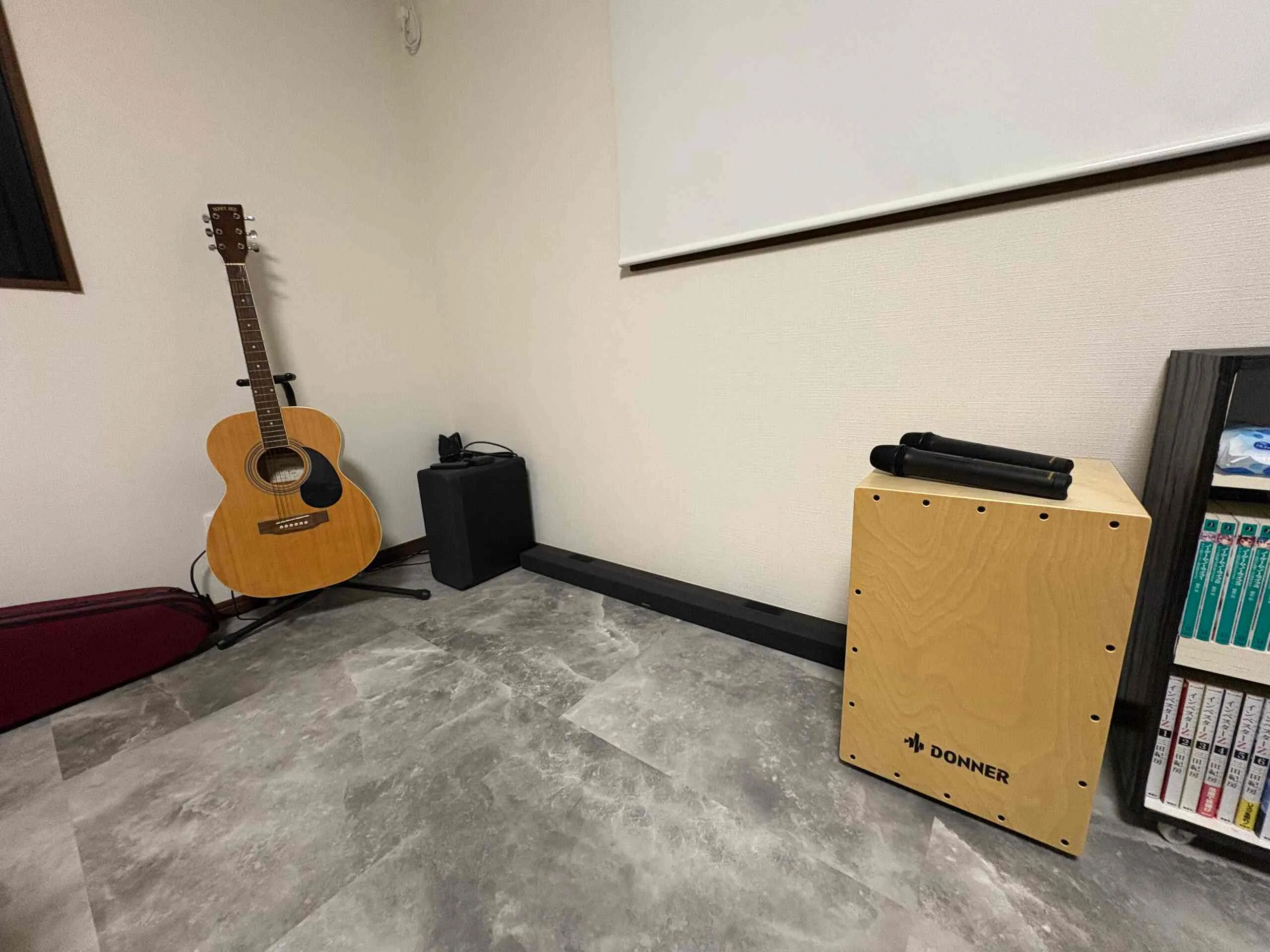 Acoustic guitar, cajon drum, and soundbar in the studio corner.